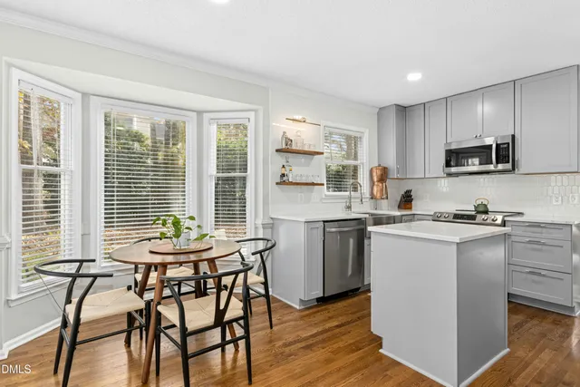 a kitchen with a table chairs microwave and cabinets