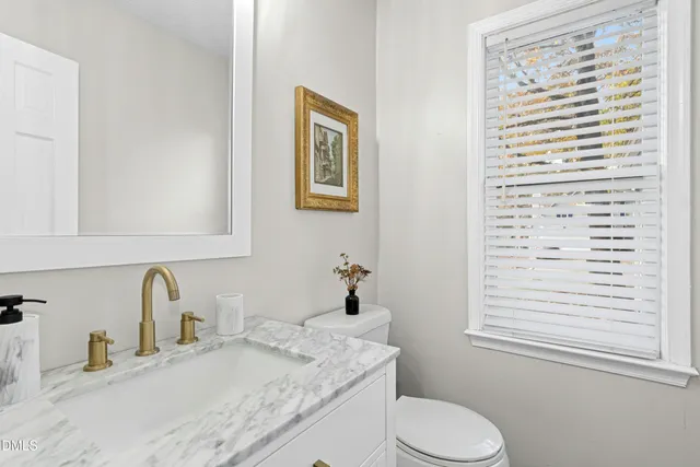 a bathroom with a granite countertop sink toilet and mirror