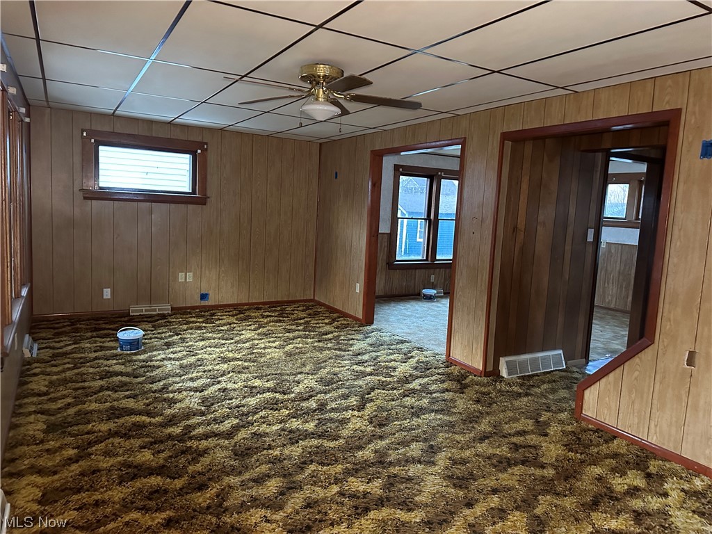 5112 Reed Avenue Ashtabula, OH 44004 - Photo 2 of 21 Carpeted spare room with wooden walls, a paneled ceiling, and ceiling fan