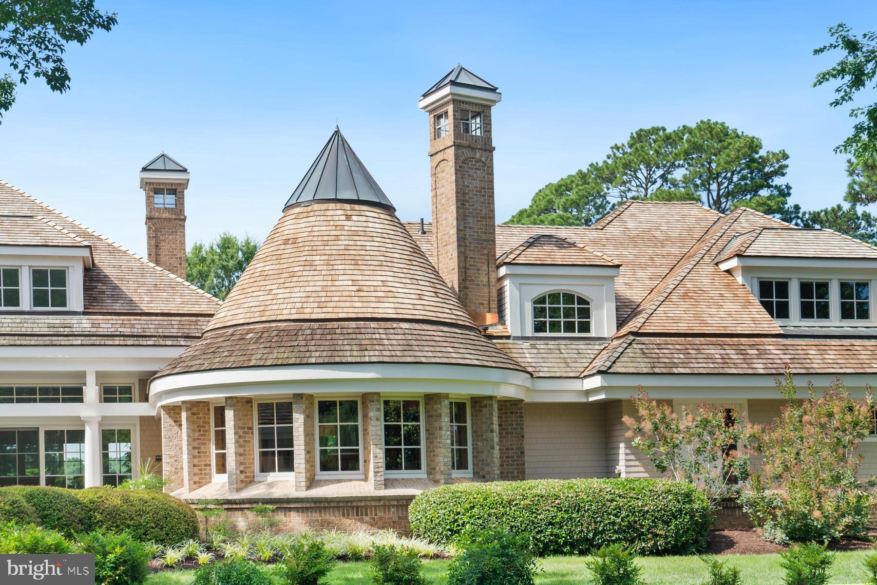7090 Cooper Point Road Bozman, MD 21612 - Photo 11 of 86 a view of a brick house with large windows and a yard with plants