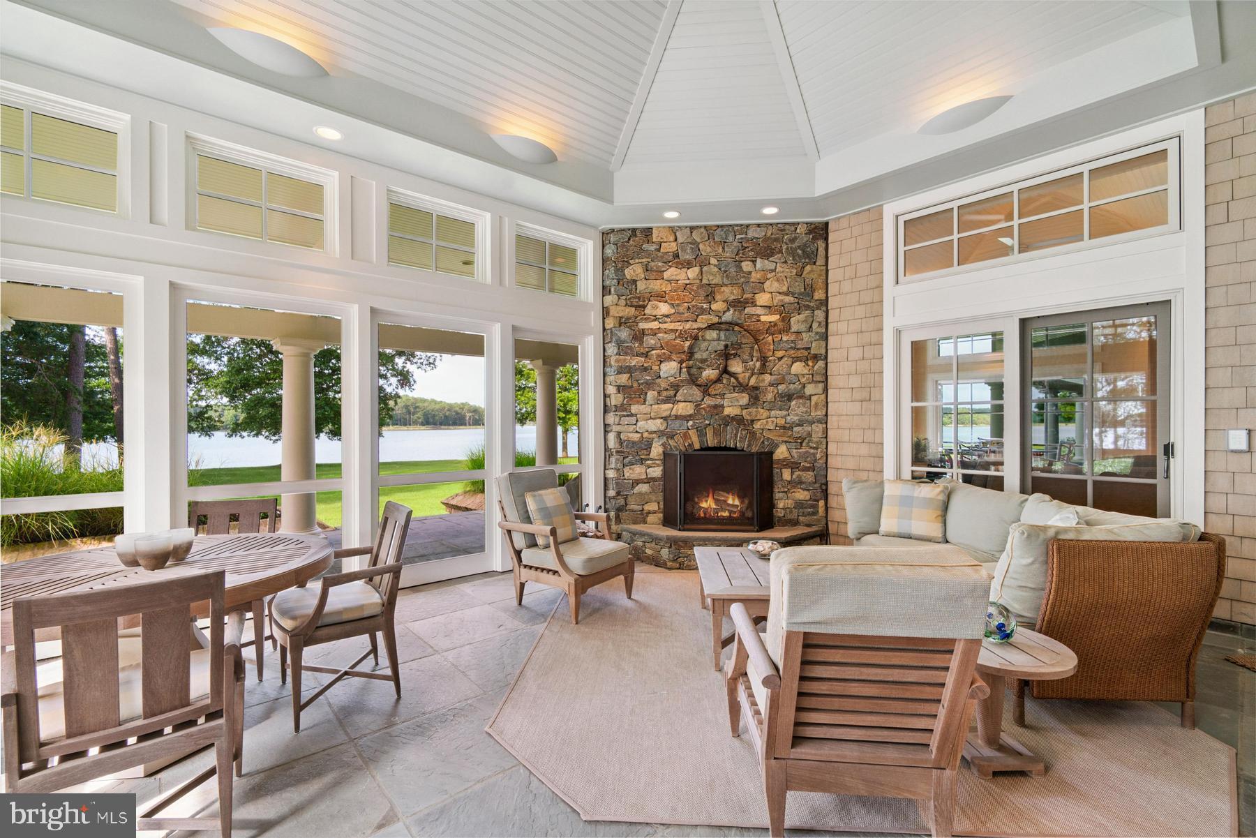7090 Cooper Point Road Bozman, MD 21612 - Photo 32 of 86 a living room with furniture a fireplace and a floor to ceiling window
