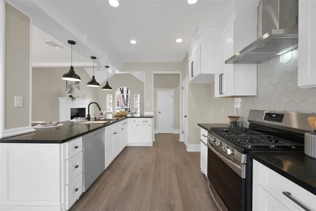 a large kitchen with stainless steel appliances granite countertop a lot of counter space and wooden floors