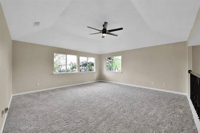 an empty room with windows and ceiling fan