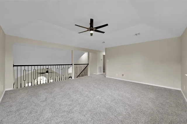 an empty room with ceiling fan and windows