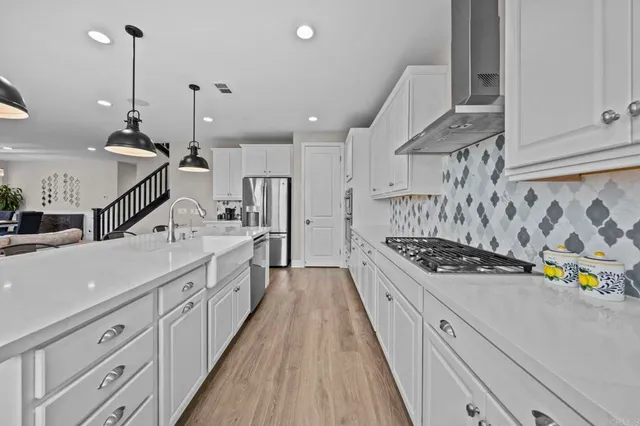 a kitchen with stainless steel appliances kitchen island a large stove a sink and white cabinets with wooden floor