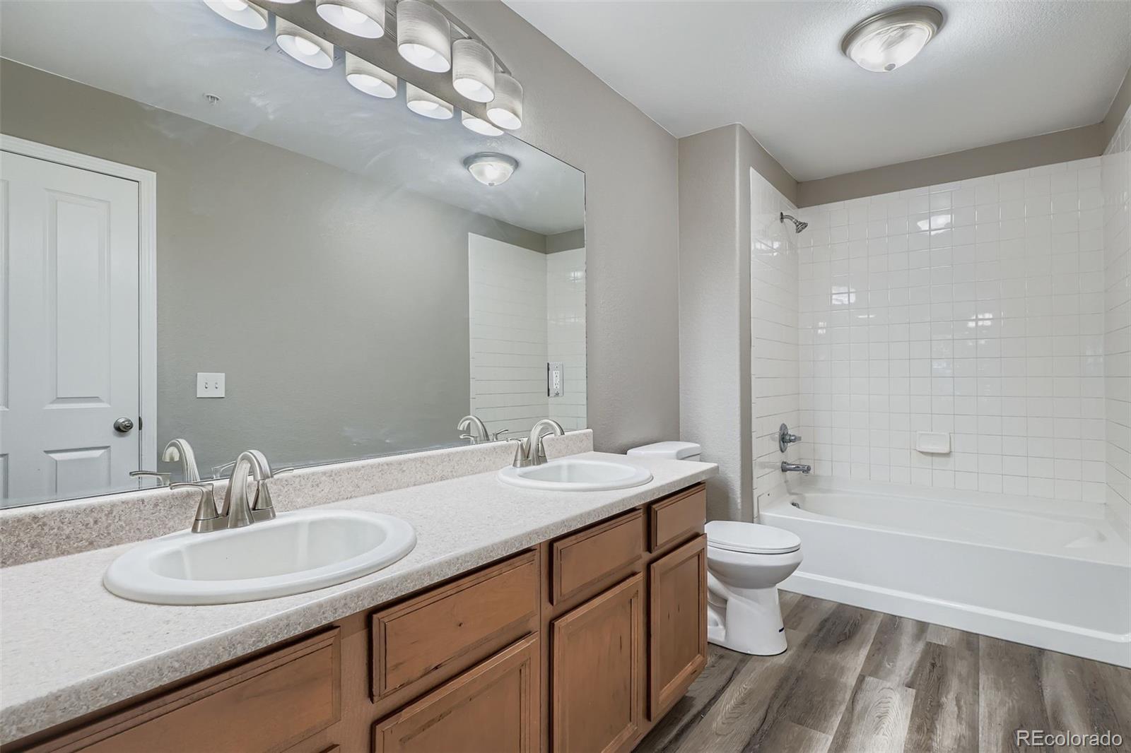 5722 South Addison Way, Unit C Aurora, CO 80016 - Photo 15 of 28 a bathroom with a double vanity sink a toilet and a large mirror