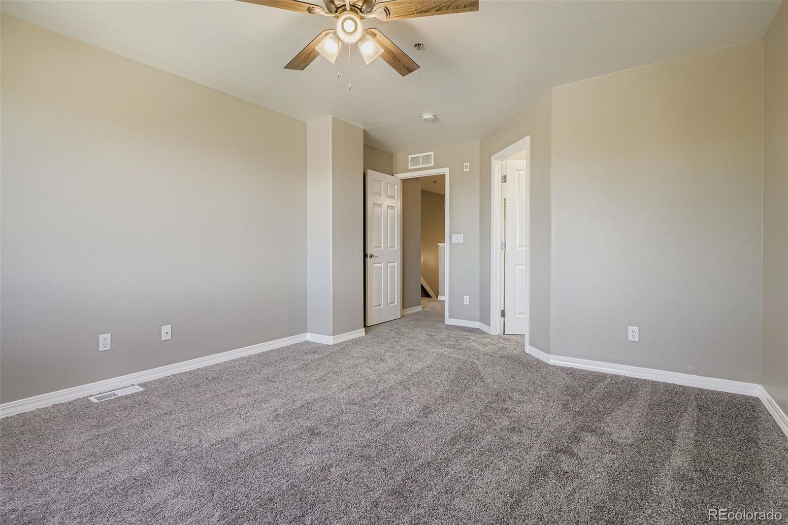 5722 South Addison Way, Unit C Aurora, CO 80016 - Photo 19 of 28 an empty room with a chandelier fan and windows