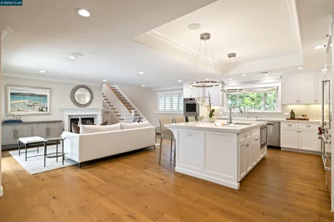a large white kitchen with wooden floor and stainless steel appliances