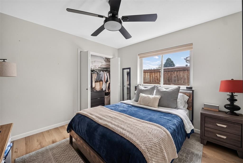 3919 Ridgeoak Way Farmers Branch, TX 75244 - Photo 20 of 28 Bedroom featuring light wood-finish flooring, a ceiling fan with integrated lighting, a built-in closet with bifold doors, and a large window