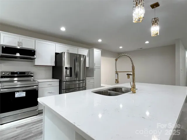 a kitchen with stainless steel appliances granite countertop a refrigerator a stove a sink and a microwave