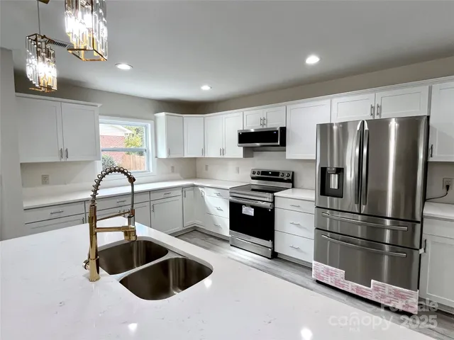 a kitchen with granite countertop a refrigerator stove and microwave