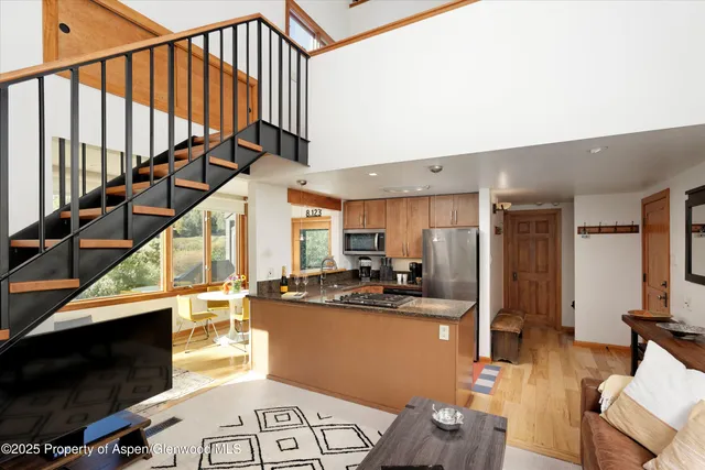 a kitchen with stainless steel appliances kitchen island granite countertop a refrigerator a stove a microwave oven with white cabinets and wooden floor