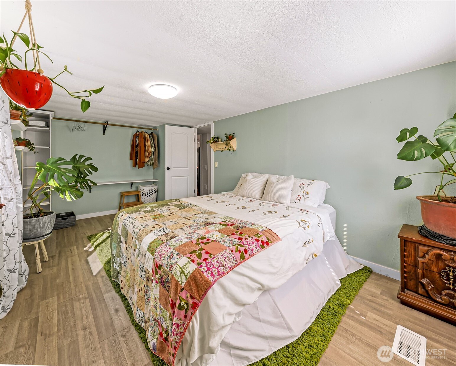 1014 West Smith Road, Unit 36 Bellingham, WA 98226 - Photo 19 of 32 a bedroom with a bed potted plant on dresser and a wooden floor