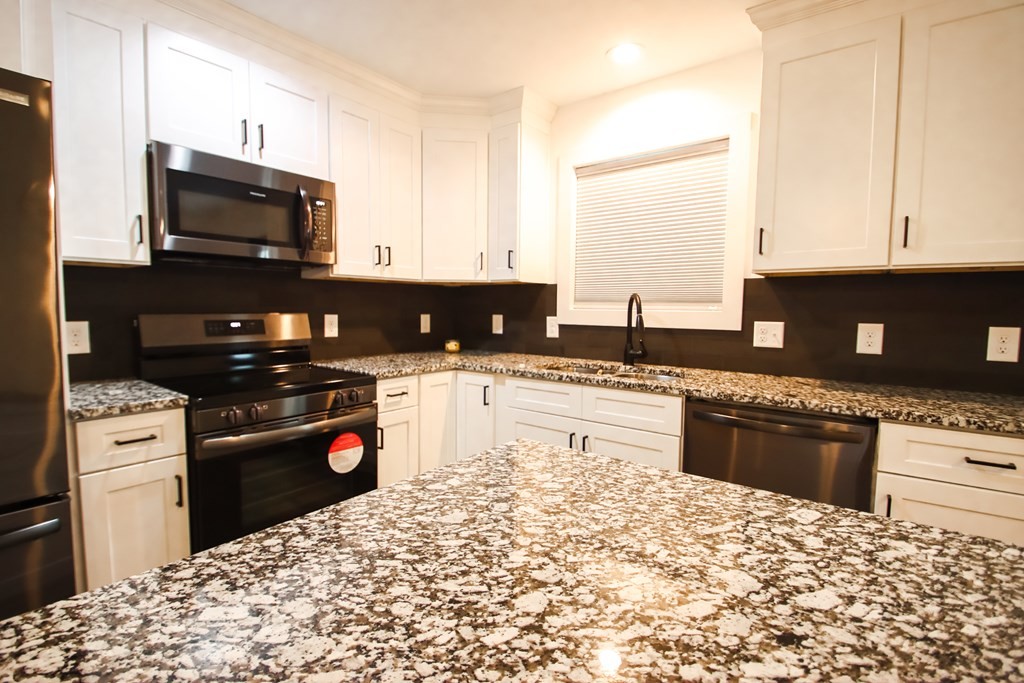 191 Rustling Oaks Drive Sparta, TN 38583 - Photo 11 of 20 a kitchen with granite countertop a stove top oven microwave and refrigerator