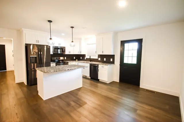 a kitchen with stainless steel appliances granite countertop a sink refrigerator and cabinets