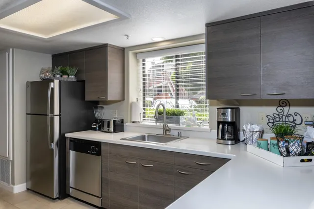 a kitchen with stainless steel appliances granite countertop a refrigerator a sink a stove and a wooden floors