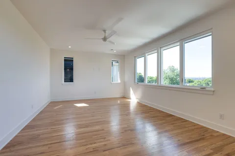 an empty room with wooden floor and windows