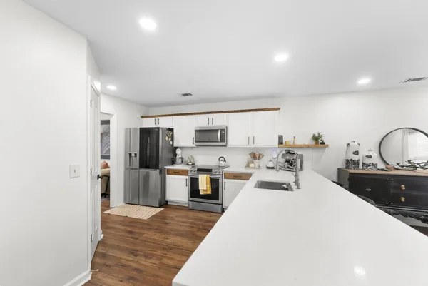 a large room with kitchen island a stove a sink a refrigerator and cabinets