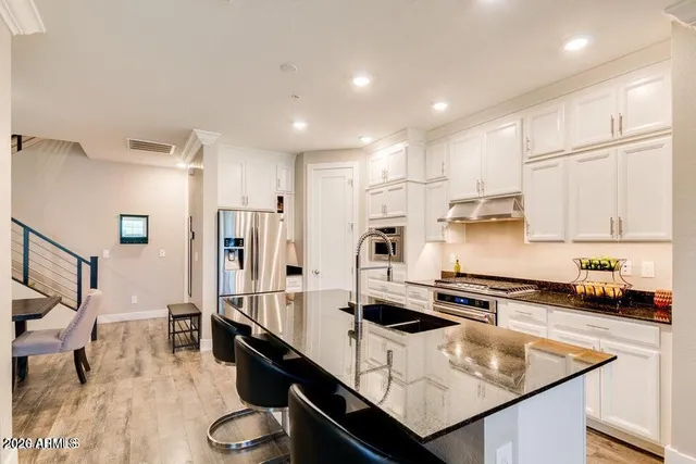 a kitchen with stainless steel appliances granite countertop a sink refrigerator and cabinets