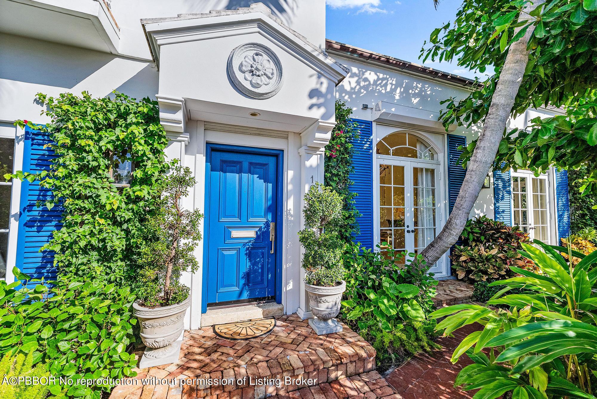 165 Root Trail Palm Beach, FL 33480 - Photo 3 of 26 a view of a house with potted plants and a clock on the wall