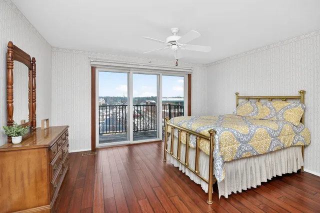 a bedroom with a bed and a large window with wooden floor