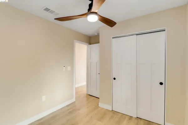 a view of empty room with wooden floor and fan