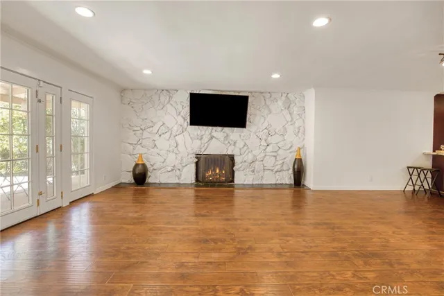 a view of an empty room with window and wooden floor