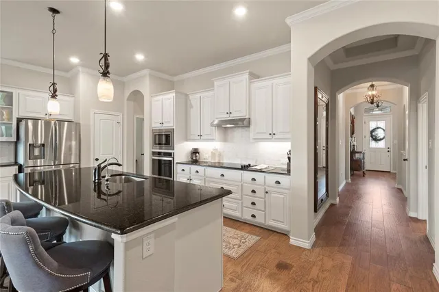 a kitchen with stainless steel appliances granite countertop a sink a stove and a wooden floors