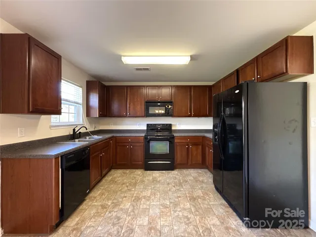 a kitchen with stainless steel appliances granite countertop a stove refrigerator and sink