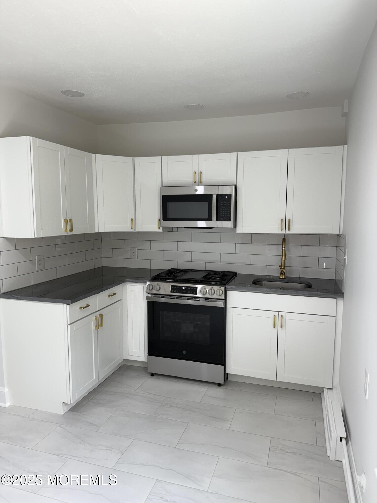 a kitchen with granite countertop white cabinets and stainless steel appliances