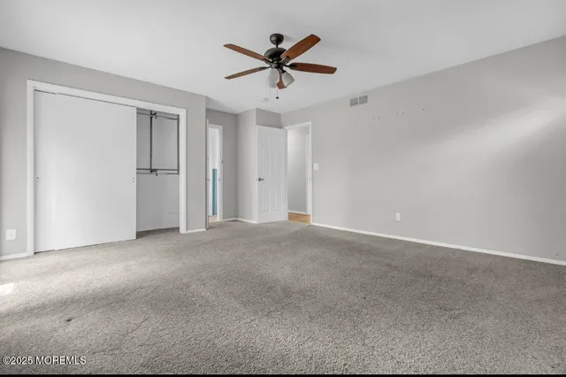 an empty room with closet and ceiling fan
