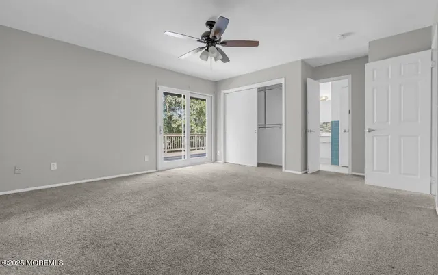 a view of a livingroom with a ceiling fan & windows