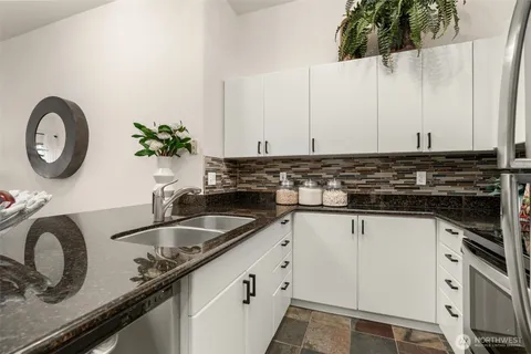 a kitchen with granite countertop a sink a stove and cabinets