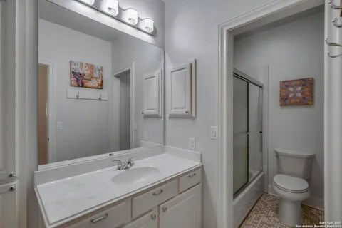 a bathroom with a granite countertop sink toilet and a mirror