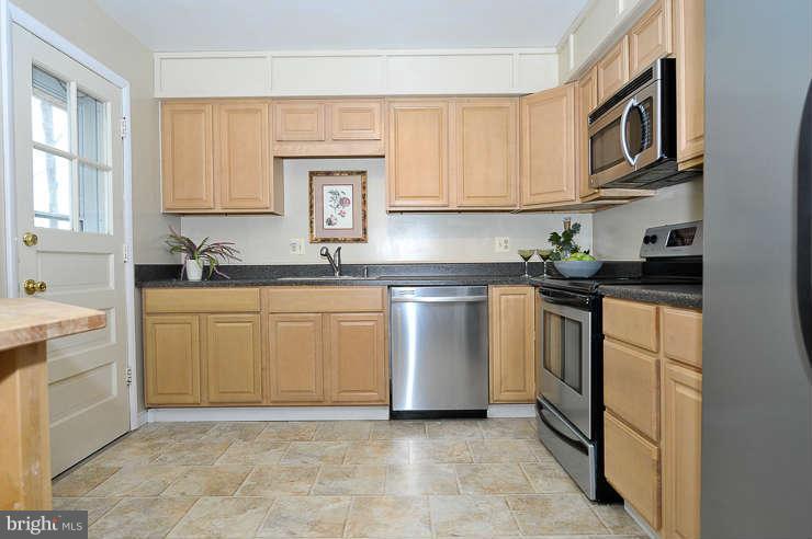5613 Rathbone Place Springfield, VA 22151 - Photo 7 of 22 a kitchen with white cabinets sink and stainless steel appliances
