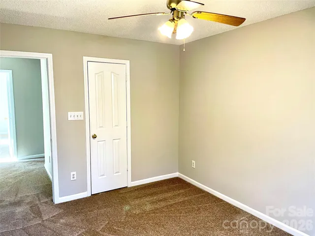 an empty room with a ceiling fan and a window