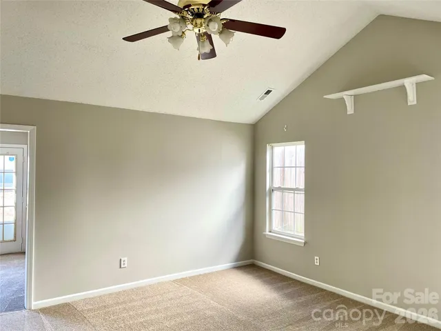 a view of a big room with a ceiling fan and windows