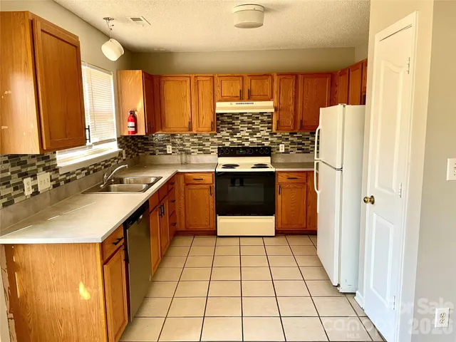 a kitchen with a sink a stove a refrigerator and a window
