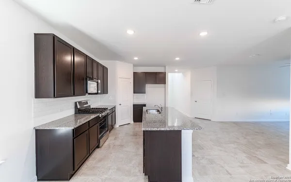 a kitchen with stainless steel appliances kitchen island granite countertop a sink and a refrigerator