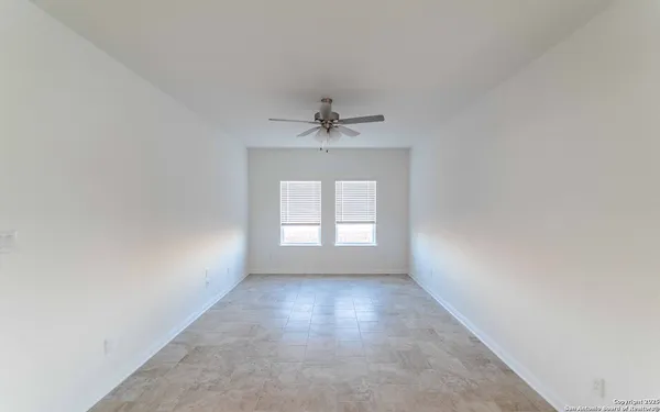 an empty room with a window and a ceiling fan