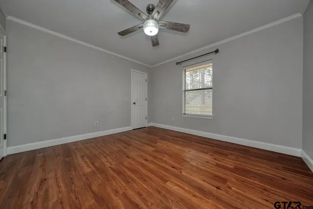 a view of empty room with wooden floor and fan