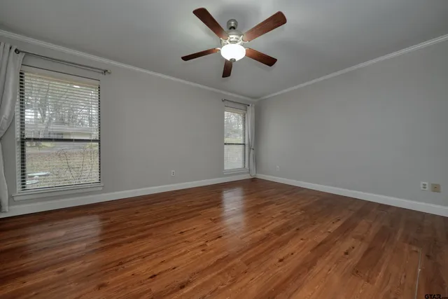 a view of an empty room with wooden floor and a window