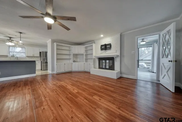 a view of empty room with wooden floor fireplace and window
