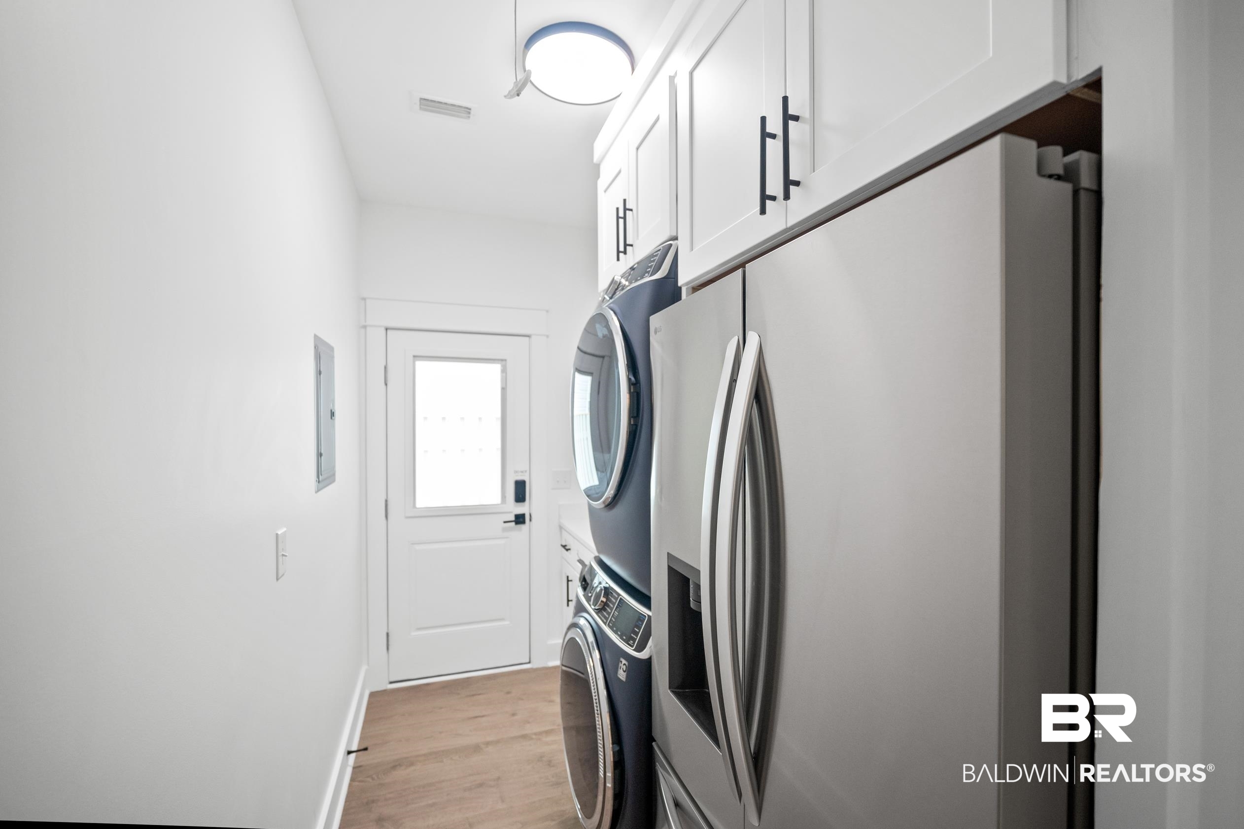 5501 Mobile Avenue Orange Beach, AL 36561 - Photo 19 of 40 Laundry room with stacked washer and clothes dryer and light wood-style flooring