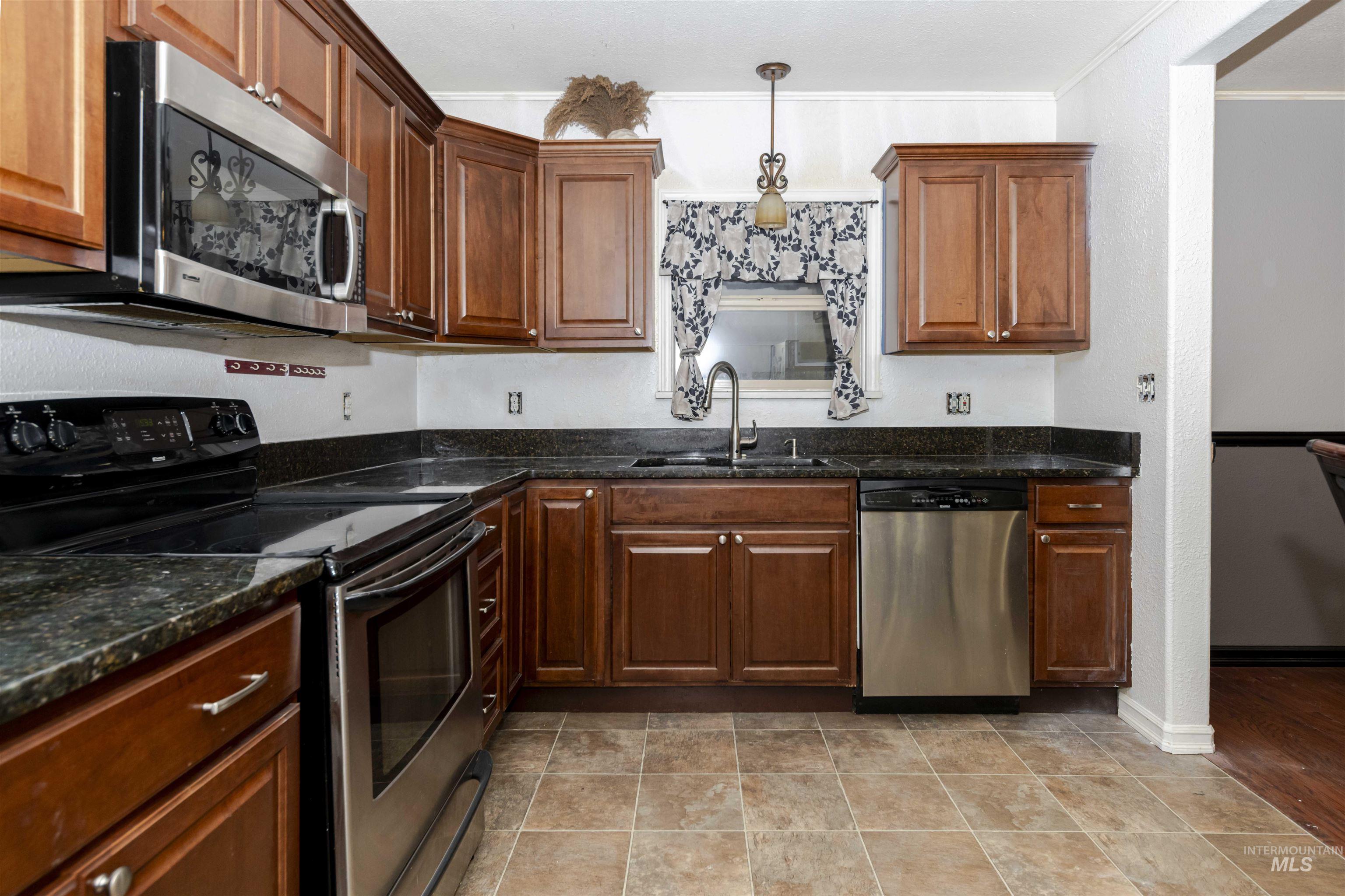 1906 15th Avenue Lewiston, ID 83501 - Photo 3 of 18 Kitchen featuring stainless steel appliances, dark stone countertops, decorative light fixtures, and crown molding