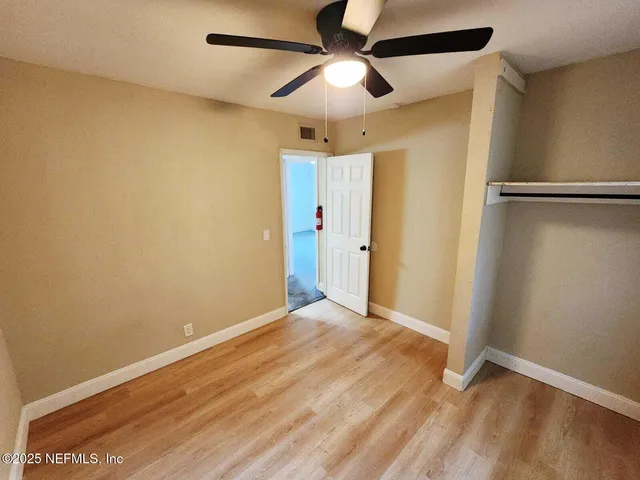 an empty room with a ceiling fan and a carpet
