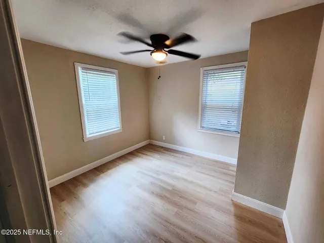 a view of an empty room with wooden floor and a window