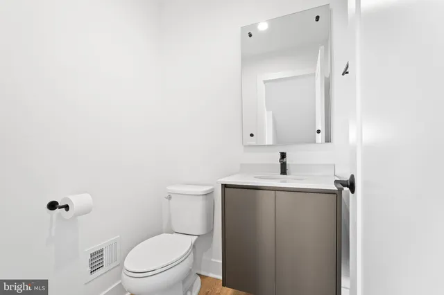 a bathroom with a toilet a sink a mirror and vanity