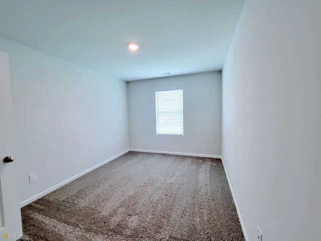an empty room with windows and chandelier fan