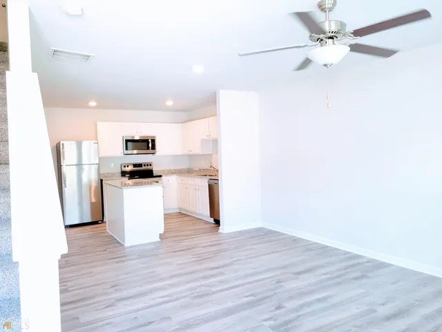a view of kitchen with stainless steel appliances refrigerator stove microwave and cabinets